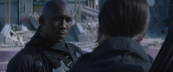 Movie still from “The Hunger Games: Mockingjay - Part 2” (2015), directed by Francis Lawrence – A man and a woman standing next to each other in front of a building; Close Up shot, Over the shoulder angle