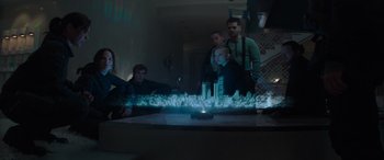Movie still from “The Hunger Games: Mockingjay - Part 2” (2015), directed by Francis Lawrence – A group of people standing in front of a lighted city model; Wide shot, Low angle