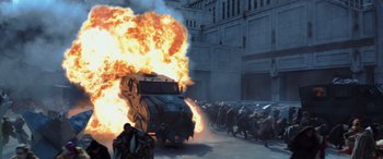 Movie still from “The Hunger Games: Mockingjay - Part 2” (2015), directed by Francis Lawrence – A large fire is coming out of the back of an armored vehicle; Wide shot, Low angle