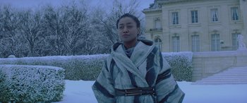 Movie still from “The Hunger Games: Mockingjay - Part 2” (2015), directed by Francis Lawrence – A woman wearing a robe in the snow outside; Medium shot, Low angle