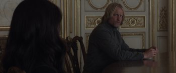 Movie still from “The Hunger Games: Mockingjay - Part 2” (2015), directed by Francis Lawrence – A man sitting at a dining room table with a woman; Medium shot, Over the shoulder angle