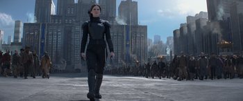 Movie still from “The Hunger Games: Mockingjay - Part 2” (2015), directed by Francis Lawrence – A woman in a black outfit walking in front of a group of people; Wide shot, Low angle