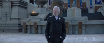 Movie still from “The Hunger Games: Mockingjay - Part 2” (2015), directed by Francis Lawrence – An older man standing in front of a fountain; Medium shot, Low angle