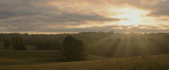 Movie still from “The Hunger Games: Mockingjay - Part 2” (2015), directed by Francis Lawrence – The sun is setting over a field with trees; Extreme Wide shot, Low angle