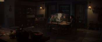 Movie still from “The Hunger Games: Mockingjay - Part 2” (2015), directed by Francis Lawrence – A group of people sitting at a table in a dark room; Wide shot, High angle