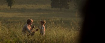 Movie still from “The Hunger Games: Mockingjay - Part 2” (2015), directed by Francis Lawrence – A woman and a little girl in a grassy field; Wide shot, Over the shoulder angle