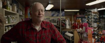 Movie still from “The Hunt” (2020), directed by Craig Zobel – An older man wearing a red plaid shirt and glasses; Close Up shot, Over the shoulder angle