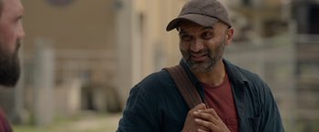 Movie still from “The Hunt” (2020), directed by Craig Zobel – A man wearing a hat and a backpack; Close Up shot, Over the shoulder angle