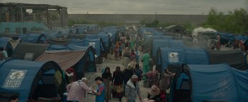 Movie still from “The Hunt” (2020), directed by Craig Zobel – A group of people walking around a tent city; Extreme Wide shot, High angle