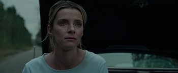Movie still from “The Hunt” (2020), directed by Craig Zobel – A woman sitting in front of a white car; Close Up shot, Low angle