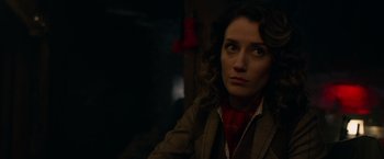 Movie still from “The Hunt” (2020), directed by Craig Zobel – A woman with curly brown hair wearing a brown jacket and a red neck tie; Close Up shot, Over the shoulder angle