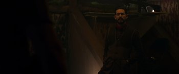 Movie still from “The Hunt” (2020), directed by Craig Zobel – A man standing next to a wall in a dark room; Medium shot, Low angle