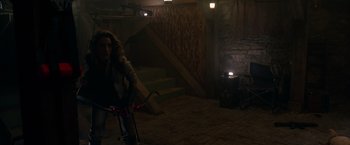 Movie still from “The Hunt” (2020), directed by Craig Zobel – A woman riding a bike inside of a building; Wide shot, High angle