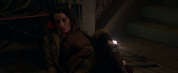 Movie still from “The Hunt” (2020), directed by Craig Zobel – A woman sitting on a couch looking at her cell phone; Medium shot, High angle