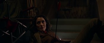 Movie still from “The Hunt” (2020), directed by Craig Zobel – A woman with a bow and arrow sitting in a chair; Medium shot, Over the shoulder angle