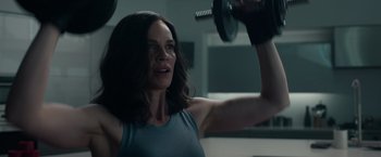 Movie still from “The Hunt” (2020), directed by Craig Zobel – A woman is lifting a dumbbell in a gym; Medium shot, Low angle