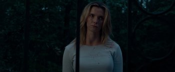 Movie still from “The Hunt” (2020), directed by Craig Zobel – A young woman is standing in front of a window; Close Up shot, Low angle