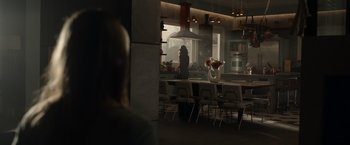 Movie still from “The Hunt” (2020), directed by Craig Zobel – A woman standing in a kitchen next to a counter; Extreme Wide shot, Over the shoulder angle