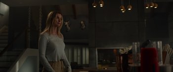 Movie still from “The Hunt” (2020), directed by Craig Zobel – A woman standing in front of a table in a room; Medium shot, Low angle