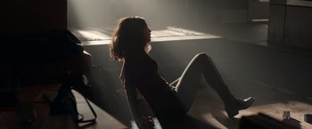 Movie still from “The Hunt” (2020), directed by Craig Zobel – A woman sitting on the ground in the sunlight; Wide shot, Low angle