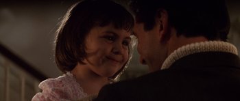 Movie still from “The Hunt for Red October” (1990), directed by John McTiernan – A little girl smiling at the camera with a man in the background; Close Up shot, Over the shoulder angle