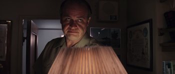 Movie still from “The Hunt for Red October” (1990), directed by John McTiernan – A man is looking at the camera while standing in front of a lamp; Close Up shot, Low angle