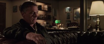 Movie still from “The Hunt for Red October” (1990), directed by John McTiernan – An older man sitting on a couch in a room; Medium shot, Over the shoulder angle