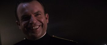 Movie still from “The Hunt for Red October” (1990), directed by John McTiernan – A man in a military uniform smiling for the camera; Close Up shot, Low angle