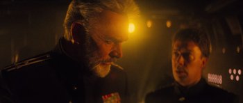 Movie still from “The Hunt for Red October” (1990), directed by John McTiernan – An older man smoking a cigarette in front of a light; Close Up shot, Over the shoulder angle