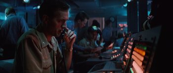 Movie still from “The Hunt for Red October” (1990), directed by John McTiernan – A group of people sitting at a table with a phone to their ear; Medium shot, Low angle