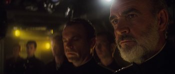 Movie still from “The Hunt for Red October” (1990), directed by John McTiernan – A group of men standing next to each other in a dark room; Close Up shot, Over the shoulder angle