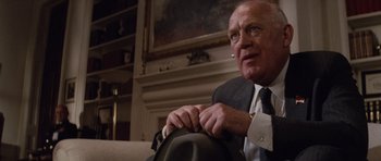 Movie still from “The Hunt for Red October” (1990), directed by John McTiernan – An older man sitting on a couch in front of a painting; Close Up shot, Over the shoulder angle