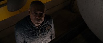 Movie still from “The Ice Road” (2021), directed by Jonathan Hensleigh – A man standing in a dark room looking up at the camera; Close Up shot, Low angle