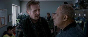 Movie still from “The Ice Road” (2021), directed by Jonathan Hensleigh – Two men talking to each other in front of a group of people; Medium shot, Over the shoulder angle