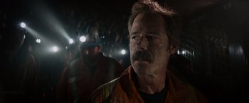 Movie still from “The Ice Road” (2021), directed by Jonathan Hensleigh – A man with a beard and mustache wearing a hard hat and safety glasses; Close Up shot, Low angle