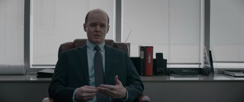 Movie still from “The Ice Road” (2021), directed by Jonathan Hensleigh – A man sitting in a chair in front of a window; Medium shot, Over the shoulder angle