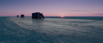 Movie still from “The Ice Road” (2021), directed by Jonathan Hensleigh – A semi truck is parked on the ice at sunset; Extreme Wide shot, High angle