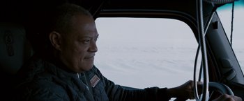Movie still from “The Ice Road” (2021), directed by Jonathan Hensleigh – An older man driving a car on a cloudy day; Close Up shot, Over the shoulder angle
