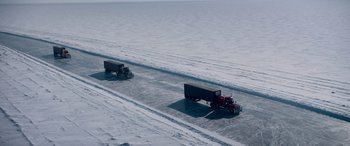 Movie still from “The Ice Road” (2021), directed by Jonathan Hensleigh – Two semi trucks driving down a snow covered road; Extreme Wide shot, High angle