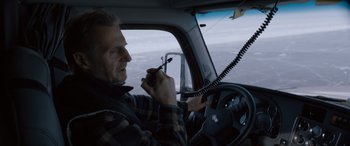 Movie still from “The Ice Road” (2021), directed by Jonathan Hensleigh – A man holding a walkie talkie while sitting in a car; Medium shot, High angle