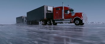 Movie still from “The Ice Road” (2021), directed by Jonathan Hensleigh – A large red truck driving down a road; Extreme Wide shot, Low angle