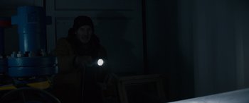 Movie still from “The Ice Road” (2021), directed by Jonathan Hensleigh – A man holding a flashlight in a dark room; Medium shot, Low angle