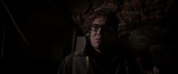 Movie still from “The Ice Road” (2021), directed by Jonathan Hensleigh – A man wearing glasses standing in the dark; Close Up shot, Low angle