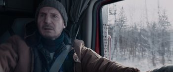 Movie still from “The Ice Road” (2021), directed by Jonathan Hensleigh – A man holding a knife while sitting in a vehicle; Close Up shot, Low angle