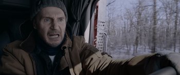 Movie still from “The Ice Road” (2021), directed by Jonathan Hensleigh – A man in a winter coat and a hat looking out of a train window; Close Up shot, Low angle