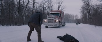 Movie still from “The Ice Road” (2021), directed by Jonathan Hensleigh – A man standing next to a truck on a snowy road; Wide shot, High angle