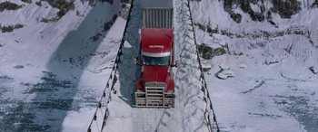 Movie still from “The Ice Road” (2021), directed by Jonathan Hensleigh – A red truck driving down a snow covered road; Extreme Wide shot, High angle