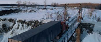 Movie still from “The Ice Road” (2021), directed by Jonathan Hensleigh – A semi truck driving over a bridge in the snow; Extreme Wide shot, High angle