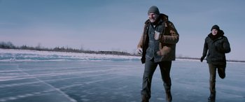 Movie still from “The Ice Road” (2021), directed by Jonathan Hensleigh – A man is walking across a frozen lake; Medium shot, Low angle