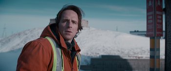 Movie still from “The Ice Road” (2021), directed by Jonathan Hensleigh – A man in a red jacket standing next to a pile of snow; Close Up shot, Low angle